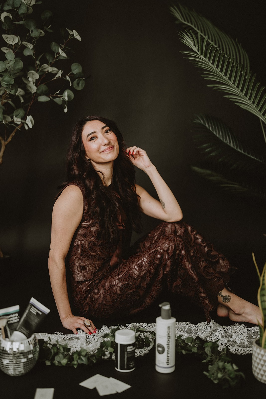 Tommi seated among greenery with professional skincare products